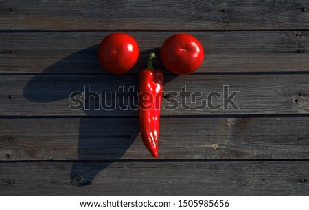 Hot red pepper with two tomatoes on a dark wooden background