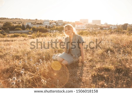Woman posing outdoor in the field of dried flowers against the sunset.