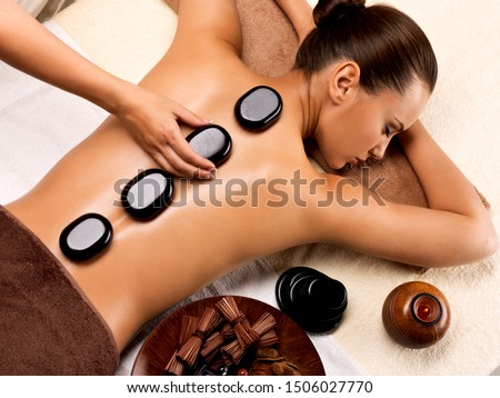 Beautiful woman relaxing in spa salon with hot stones on body. Beauty treatment therapy Royalty-Free Stock Photo #1506027770
