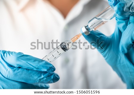 Doctor, nurse, scientist, researcher hand in blue gloves holding flu, measles, coronavirus, covid-19 vaccine disease preparing for human clinical trials vaccination shot, medicine and drug concept. Royalty-Free Stock Photo #1506051596