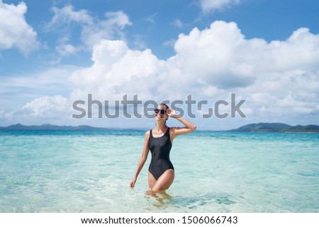 Enjoying suntan and vacation. Outdoor portrait of pretty young woman in swimsuit on beautiful tropical beach.