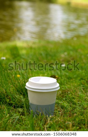 Take away coffee cup in the grass with the water in the background