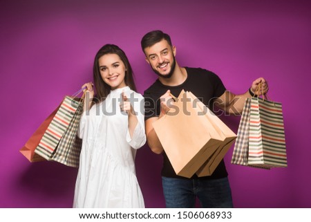 Happy beautiful couple posing with shopping bags. Smiling girl with handsome man posign together.