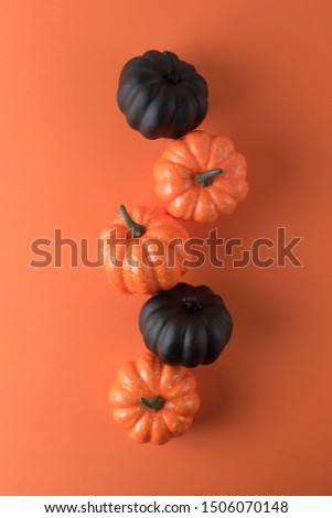 Creative layout of black and autumn pumpkins with orange background. Creative minimal concept.