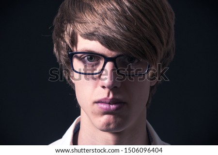 Blond boy with white shirt, suspenders and glasses photographed in studio with black background