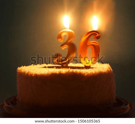 birthday cake with lit candles and number 36 on it.night scene.slow shutter speed. Thirty six years birthday.Cupcake with golden burning candle in the form of number 36. Vivid blue background 
