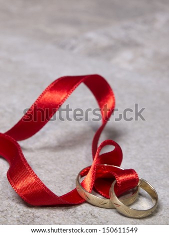 Wedding rings connected with red ribbon