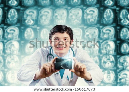 Young funny doctor taking photos with camera