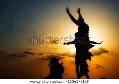 Silhouette happy family are jumping on the beautiful sunset background.