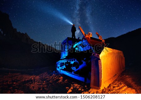 Man on bulldozer with head lamp under Milky Way view at night starry sky in the mountains 