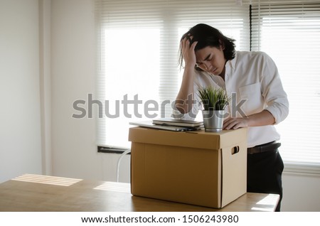 Losing job. stressed asian young employee business man leaving the office with his personal stuff carton box, financial crisis, unemployed, last day at work, fired from job and lay off concept Royalty-Free Stock Photo #1506243980