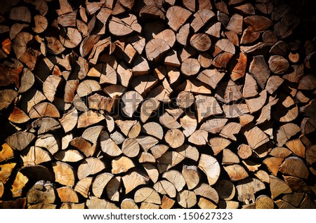 Background of dry chopped firewood logs stacked up on top of each other in a pile with vignette 