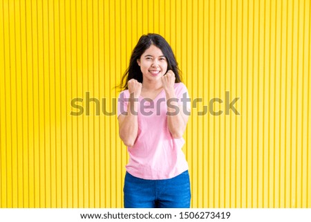 young asian woman happiness standing on yellow wall for copy sapce