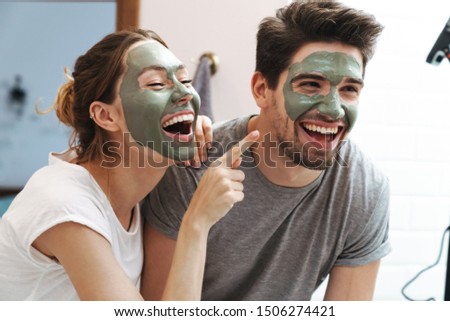 Image of caucasian couple man and woman smiling while standing in bathroom with face mask