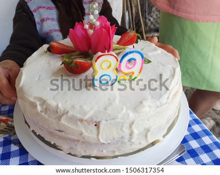 Ninety-One Birthday Cake, 91 Years Anniversary of an Grandmother, Delicious Strawberry Cake with Birthday Candles and Beautiful Flowers, the Old Woman on the Background