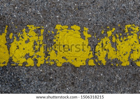 Old painted yellow line on asphalt road. Abstract texture background.