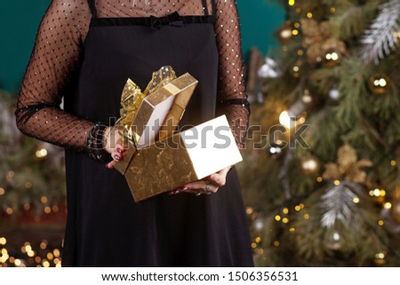 Beautiful gir opening cristmas gift box. lWoman's  hands holding gold gift box. Christmas, new year, birthday concept. Festive background with bokeh and sunlight. Magic fairy tale
