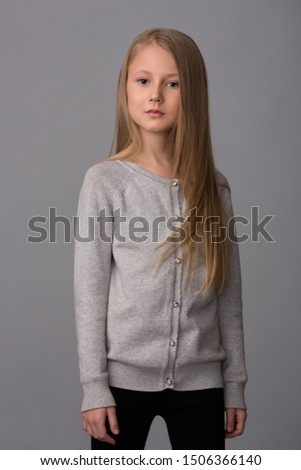 Beautiful girl child in a gray sweater and black pants
