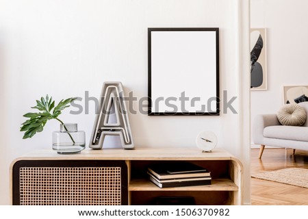 Modern scandinavian home interior with mock up photo frame, design wooden commode,  big cement letter, tropical leaf, gray sofa and personal accessories. Stylish home decor. Template. Ready to use. 