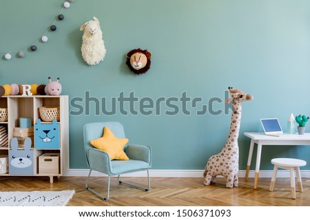 Interior design of scandinavian childroom with wooden cabinet, mint armchair, white desk, a lot of plush and wooden toys. Eucalyptus color of background walls. Plush animal head on the wall. Template 