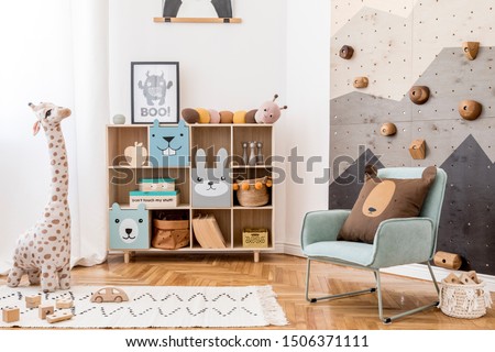Scandinavian interior design of playroom with modern climbing wall for kids, design furnitures, mint armchair, soft toys, teddy bear and cute children's accessories. Mock up poster frame. Template. Royalty-Free Stock Photo #1506371111