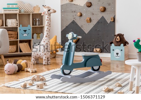 Scandinavian interior design of playroom with modern climbing wall for kids, design furnitures, kid's motor toy, soft toys, teddy bear and cute children's accessories. Stylish kidroom decor. Template.