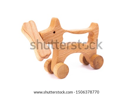 Photo of a wooden dog with bone on wheels  of beech. Toy made of wood  on a white isolated background.A toy for entertaining children and resting parents