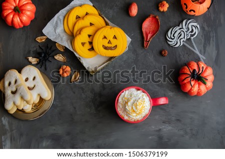 Red mug with Halloween punch and different horror cookies treat on dark background. Happy Halloween concept.
