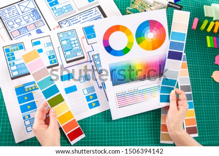 The girl works as a designer of mobile applications. Selection of the most successful color solution of the user interface. Using the color palette in the work.