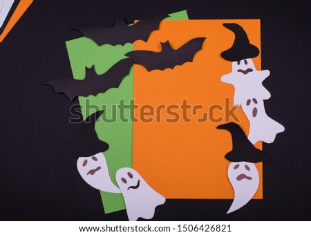 Creative congratulation card with craft paper figures of ghosts and flying bats on a black background, copy space. Flat lay.