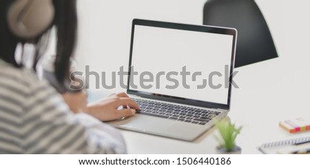 Cropped shot of young adorable female freelancer working on her project while typing on blank screen laptop computer 