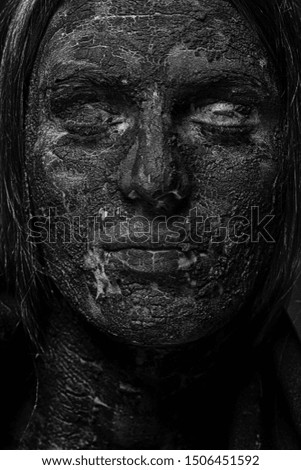 Female face covered with a layer of cracked clay.