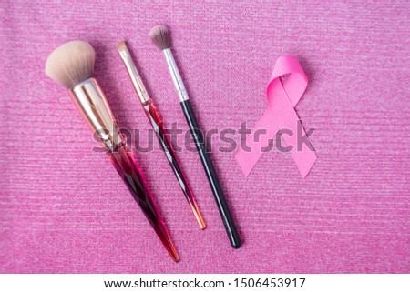 October Breast Cancer Awareness month,  Pink Ribbon and cosmetic makeup brushes on pink shirt for supporting people living and illness. Healthcare, International Women day and World cancer day concept