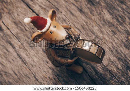 Christmas card: candle in form of mouse on background of a garland with a bokeh effect. Symbol of New year 2020 - white mouse in the clothes of Santa Claus sits in a big red xmas boot and holds a gift