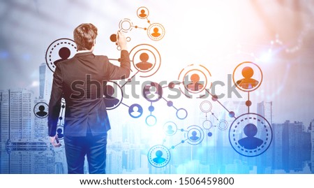 Rear view of young businessman drawing social network icons over cityscape background. Concept of HR and modern technology. Toned image double exposure
