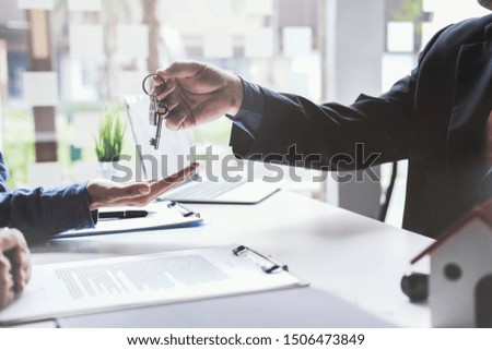 real estate agent holding house key to his client after signing contract,concept for real estate, moving home or renting property

