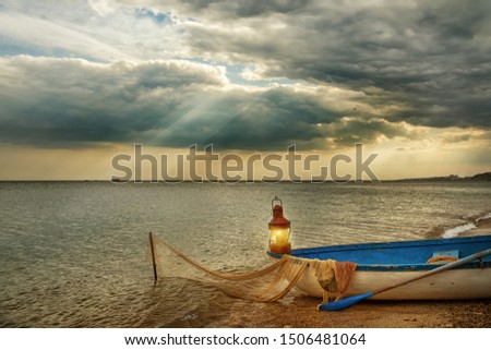 Old boat by the sea with a fishing lantern and old fishing nets. Dramatic sky. Fantastic fantastic picture of the sea landscape.
