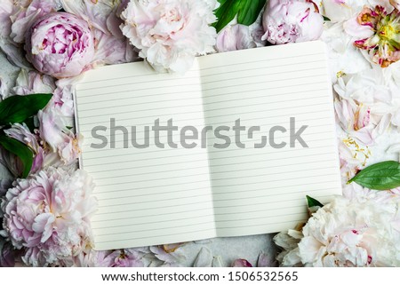 Frame made of pink peony flowers and open notebook