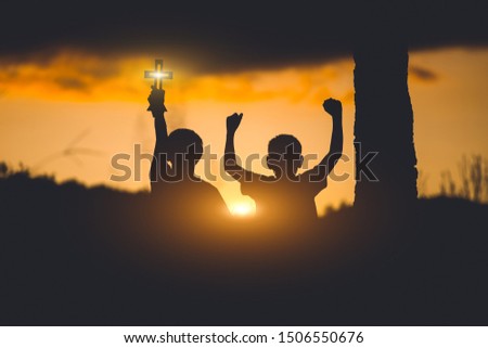 Young christian holding cross for pray to God ,christian silhouette  concept.