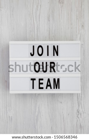 'Join our team' words on a lightbox on a white wooden background. Overhead, from above, flat lay. Close-up.