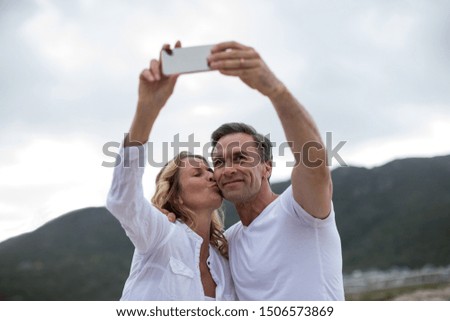 Mature couple taking selfie using mobile phone on the beach