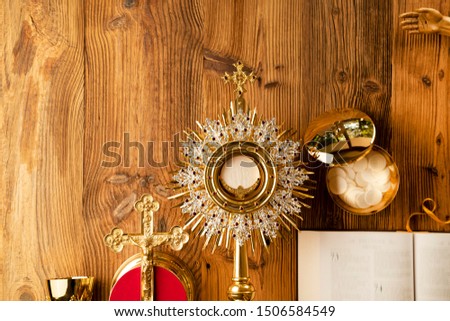 Christianity concept background. Jesus Christ, Bible and golden Christianity symbols composition: The Cross, monstrance, crucifix, chalice, relic. Wooden table. Top view Shot.