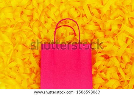 Pink shopping bag and yellow ribbons. Zero waste and No Plastic sale concept. Yellow packaging satin ribbon background. Silk mixed tape in trendy yellow color and red paper bag, copy space