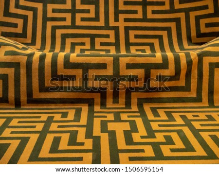 Black angular lines on an orange fabric background, ancient greek labyrinth pattern