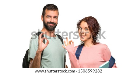 Two students with backpacks and books showing an ok sign with fingers on isolated white background