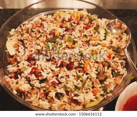 White rice, vegetables and bean salad in a large transparent bowl, with spoon.