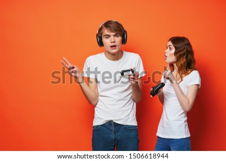 guy and girl with gamepads in hands fun games entertainment orange background hobby