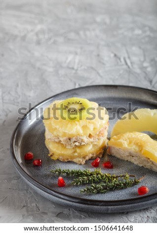 Pieces of baked pork with pineapple, cheese and kiwi on gray plate, side view, close up, selective focus, copy space.