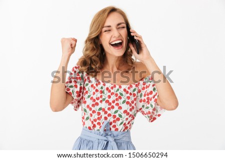 Portrait of happy young woman dressed in summer clothes rejoicing and laughing while talking on mobile phone isolated over white background