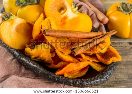 Dried persimmon fruit, with fresh persimmons, on wooden rustic background copy space